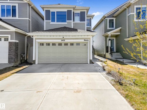 Two-story residence featuring light gray siding, white trim, and a prominent front-facing garage - 2435 12 Avenue Nw, Edmonton, AB 