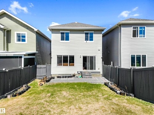 Rear exterior with a patio and grassed area, featuring a sliding glass door and multiple windows - 2435 12 Avenue Nw, Edmonton, AB 