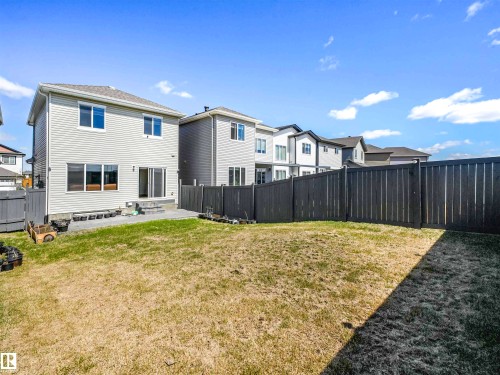 Private backyard featuring a paved patio, full fencing, and a two-story residence with light-colored siding - 2435 12 Avenue Nw, Edmonton, AB 