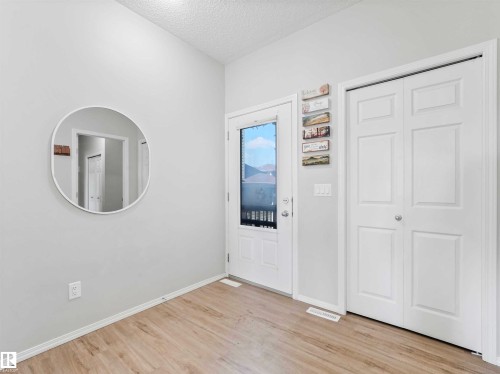 Light wood-finish flooring, white walls, and a white entry door with frosted glass panel - 2435 12 Avenue Nw, Edmonton, AB 