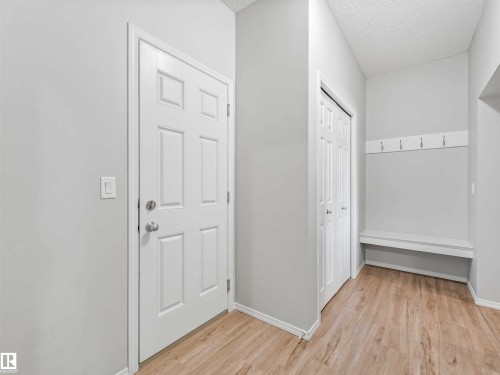 Light wood-finish flooring, built-in coat hooks, built-in bench seating, bi-fold closet doors, and a paneled entry door - 2435 12 Avenue Nw, Edmonton, AB 