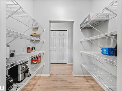 Walk-in pantry with extensive wire shelving, light wood-finish flooring, and a bifold door entry - 2435 12 Avenue Nw, Edmonton, AB 