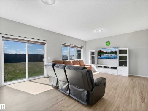 Spacious room featuring wood-finish flooring, light grey wall tones, and a sliding glass door leading to the exterior - 2435 12 Avenue Nw, Edmonton, AB 