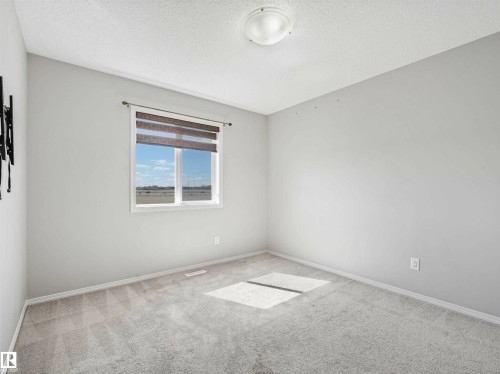 Wall-to-wall carpeting with a neutral color palette, a single window, and a ceiling-mounted light fixture - 2435 12 Avenue Nw, Edmonton, AB 