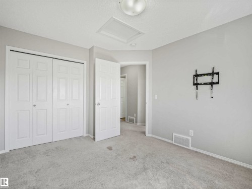 Light gray carpeting, white bi-fold closet doors, white wall-mounted light fixture, white door, and light gray wall paint - 2435 12 Avenue Nw, Edmonton, AB 