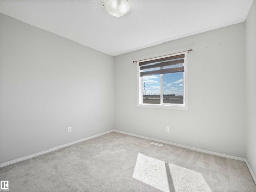Plush carpeting, neutral wall tones, modern flush-mount ceiling light fixture, and a window with roller shades - 2435 12 Avenue Nw, Edmonton, AB 