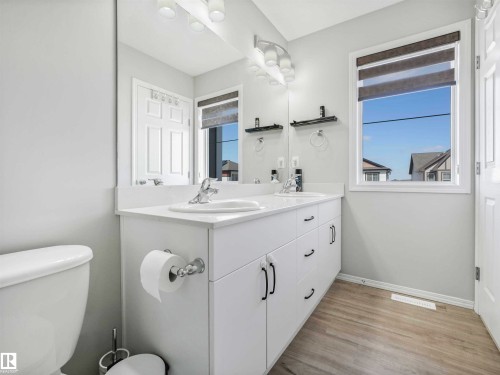 White dual vanity with integrated sinks, chrome fixtures, and wood-finish flooring - 2435 12 Avenue Nw, Edmonton, AB 