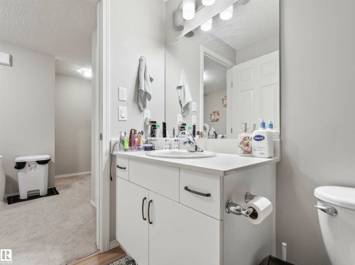 White vanity with integrated sink, chrome faucet, and overhead bar lighting - 2435 12 Avenue Nw, Edmonton, AB 