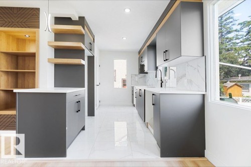 Sleek kitchen featuring dark cabinetry, white countertops, a contrasting white tile backsplash, and stainless steel appliances - 12303 131 St Nw Nw, Edmonton, AB 