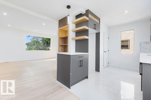 Modern kitchen and living space with light wood-finish flooring, recessed lighting, white walls, and a contemporary pendant light fixture - 12303 131 St Nw Nw, Edmonton, AB 