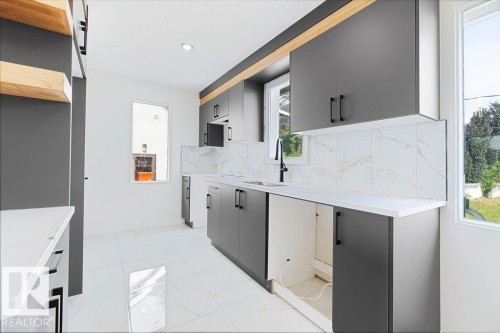 Modern kitchen featuring gray flat-panel cabinetry, white countertops, and a white tile backsplash - 12303 131 St Nw Nw, Edmonton, AB 