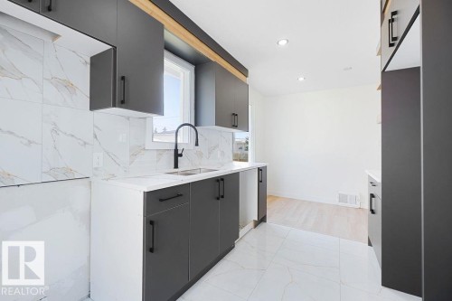 Contemporary kitchen featuring matte dark gray cabinetry, white marble-look countertops, white tiled flooring, and a matte black gooseneck faucet - 12303 131 St Nw Nw, Edmonton, AB 