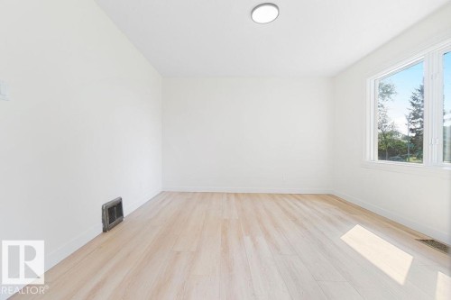 Bright room featuring white walls, wood-finish flooring, and a large window - 12303 131 St Nw Nw, Edmonton, AB 