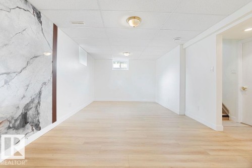 Wood-finish flooring, white walls, drop ceiling, recessed window, and decorative wall panel with sconces - 12303 131 St Nw Nw, Edmonton, AB 