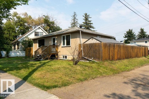 Stucco exterior with multiple windows, leading to a wood-plank deck and stairs - 12303 131 St Nw Nw, Edmonton, AB 