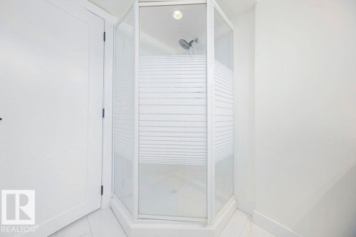 Corner glass-enclosed shower with a white tile base and a chrome shower head - 12303 131 St Nw Nw, Edmonton, AB 