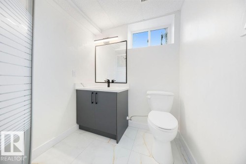 Modern vanity with a rectangular basin, black framed mirror, and white tile flooring - 12303 131 St Nw Nw, Edmonton, AB 