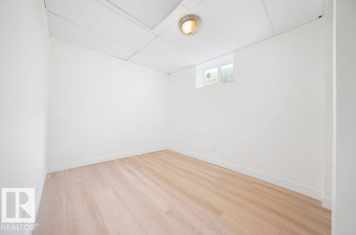 Light wood-finish flooring, white walls, drop ceiling, and a wall-mounted light fixture - 12303 131 St Nw Nw, Edmonton, AB 