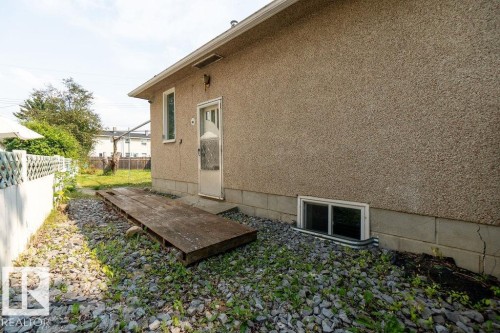 Exterior wall with stippled finish, side entrance, and single basement window - 12303 131 St Nw Nw, Edmonton, AB 