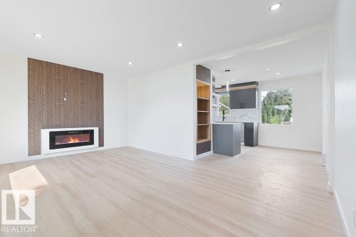 Recessed lighting, light wood-finish flooring, accent wall with geometric pattern, built-in electric fireplace, and dark-toned cabinetry - 12303 131 St Nw Nw, Edmonton, AB 