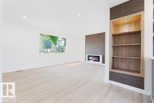 Recessed lighting, light wood-finish flooring, built-in shelving with accent lighting, and a modern fireplace with a patterned accent wall - 12303 131 St Nw Nw, Edmonton, AB 