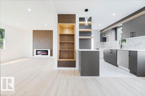 Integrated kitchen and living area featuring wood-finish flooring, a contemporary fireplace, built-in shelving, dark-toned cabinetry, and a full backsplash - 12303 131 St Nw Nw, Edmonton, AB 