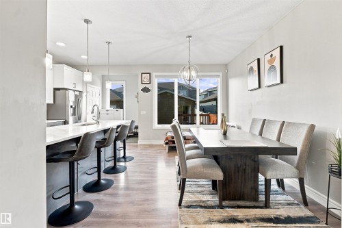 Kitchen island with a white countertop, wood-finish flooring, and pendant lighting - 8024 Orchards Green Green Sw, Edmonton, AB 