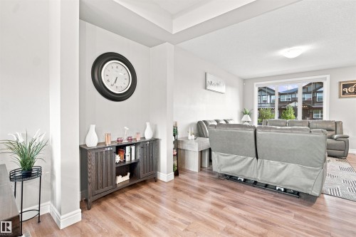 Wood-finish flooring throughout, tray ceiling, and white trim - 8024 Orchards Green Green Sw, Edmonton, AB 