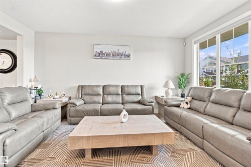Bright living area with light-toned walls and a large window - 8024 Orchards Green Green Sw, Edmonton, AB 