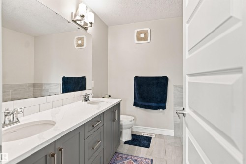Dual vanity with undermount sinks, white countertop, and subway tile backsplash - 8024 Orchards Green Green Sw, Edmonton, AB 