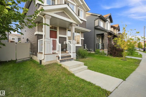 Covered front porch with white railings, concrete steps, and a red entry door - 8024 Orchards Green Green Sw, Edmonton, AB 