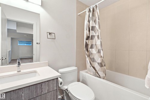 Bathroom featuring a white vanity with an integrated sink, polished chrome faucet, and wood-finish cabinetry - 8024 Orchards Green Green Sw, Edmonton, AB 