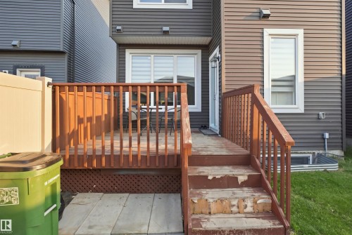 Wood-finish deck with railing, leading to a sliding glass door - 8024 Orchards Green Green Sw, Edmonton, AB 