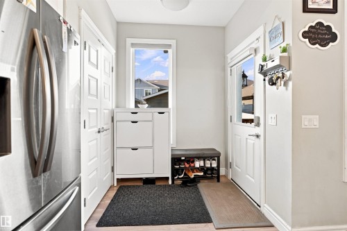 Entryway featuring a white door with an inset window, light wood-finish flooring, and light gray wall paint - 8024 Orchards Green Green Sw, Edmonton, AB 