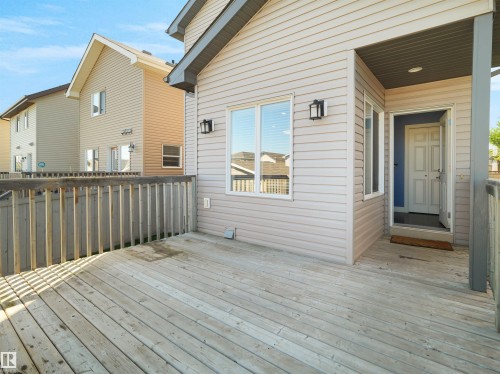Wood deck with wood railing, leading to an entryway with an overhead light fixture - 5190 1B Avenue Sw, Edmonton, AB 