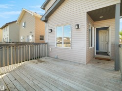 Wood deck with wood railing, leading to an entryway with an overhead light fixture - 