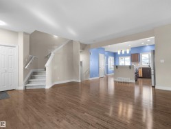 Wood-finish flooring, staircase with carpeted treads, white painted trim, white panel doors, and recessed lighting - 