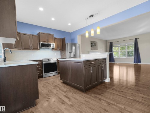 Wood-finish flooring, recessed lighting, and a kitchen island with pendant lighting - 5190 1B Avenue Sw, Edmonton, AB 