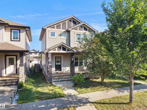 Two-story residence featuring siding exterior, stone facade accents, covered front porch, and mature landscaping - 5190 1B Avenue Sw, Edmonton, AB 