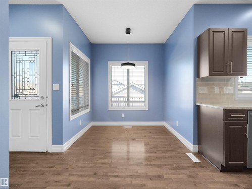 Wood-finish flooring, white trim, and a modern pendant light fixture - 5190 1B Avenue Sw, Edmonton, AB 