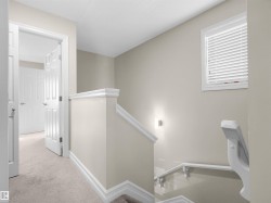 Hallway with neutral carpeting, white trim, and a window with blinds - 