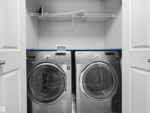 Laundry closet with bi-fold doors, wire shelving, and overhead cabinet - 5190 1B Avenue Sw, Edmonton, AB 