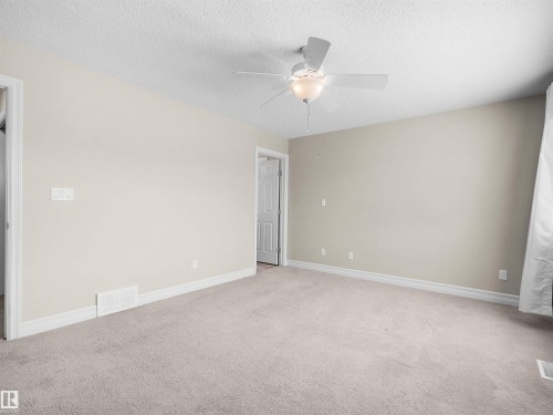 Neutral-toned walls, light-colored carpeting, white trim, and a ceiling fan with integrated lighting - 5190 1B Avenue Sw, Edmonton, AB 