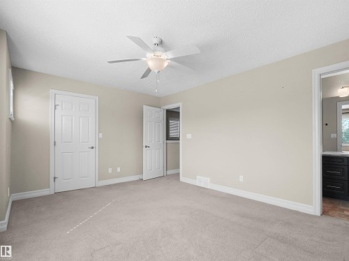 Neutral wall paint, plush carpet flooring, ceiling fan with integrated lighting, white trim, and white paneled doors - 5190 1B Avenue Sw, Edmonton, AB 