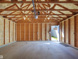 Exposed wood framing, concrete flooring, overhead lighting, and an automatic garage door opener - 
