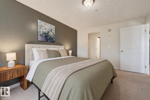 Bedroom featuring an upholstered headboard, a neutral color palette, and wall-to-wall carpeting - #314 245 Edwards Dr Sw, Edmonton, AB - Indoor Photo Showing Bedroom