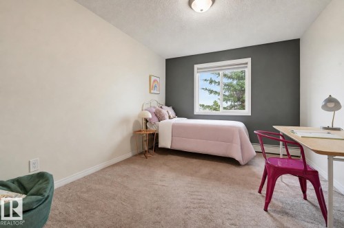 Bedroom featuring a large window, neutral carpeting, light-colored walls, and a contrasting accent wall - #314 245 Edwards Dr Sw, Edmonton, AB - Indoor Photo Showing Bedroom