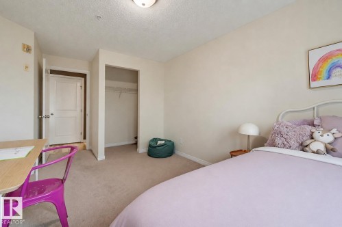 Light-toned wall paint throughout, carpet flooring, a built-in closet with a wire rack, and a classic interior door with a silver doorknob - #314 245 Edwards Dr Sw, Edmonton, AB - Indoor Photo Showing Bedroom