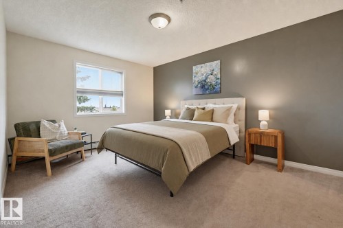 Carpeted bedroom featuring a window, light-colored walls, and a feature wall in a muted tone - #314 245 Edwards Dr Sw, Edmonton, AB - Indoor Photo Showing Bedroom