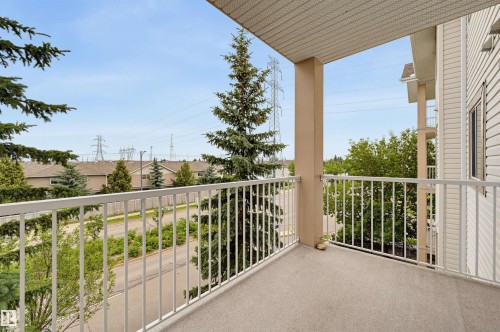 Private balcony featuring a textured floor, white metal railing, and a neutral-toned support column - #314 245 Edwards Dr Sw, Edmonton, AB - Outdoor With Exterior